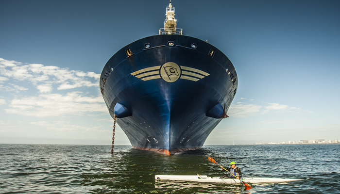 Richard Kohler paddling past a container ship bow