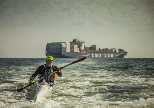 Richard Kohler paddling past a container ship on the KwaZulu-Natal coast