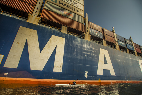 Richard Kohler paddling beneath a container ship's bow on the Wild Coast